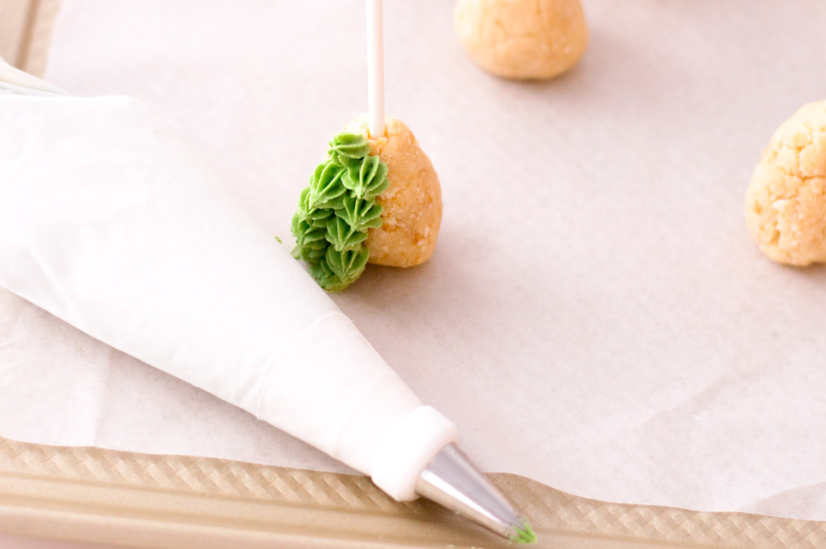 piping green frosting on cake pop